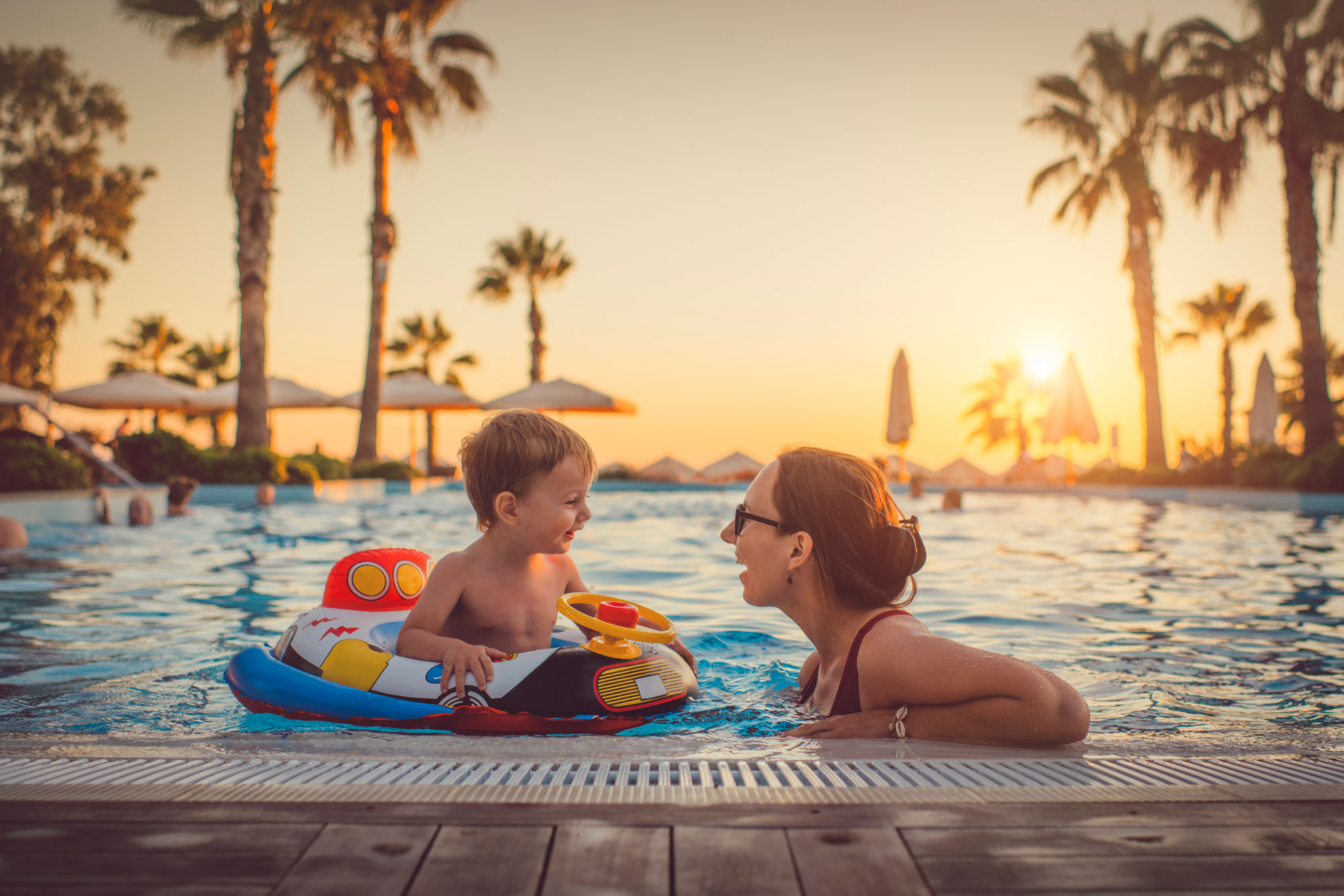 En mor och son badar i en pool på semester